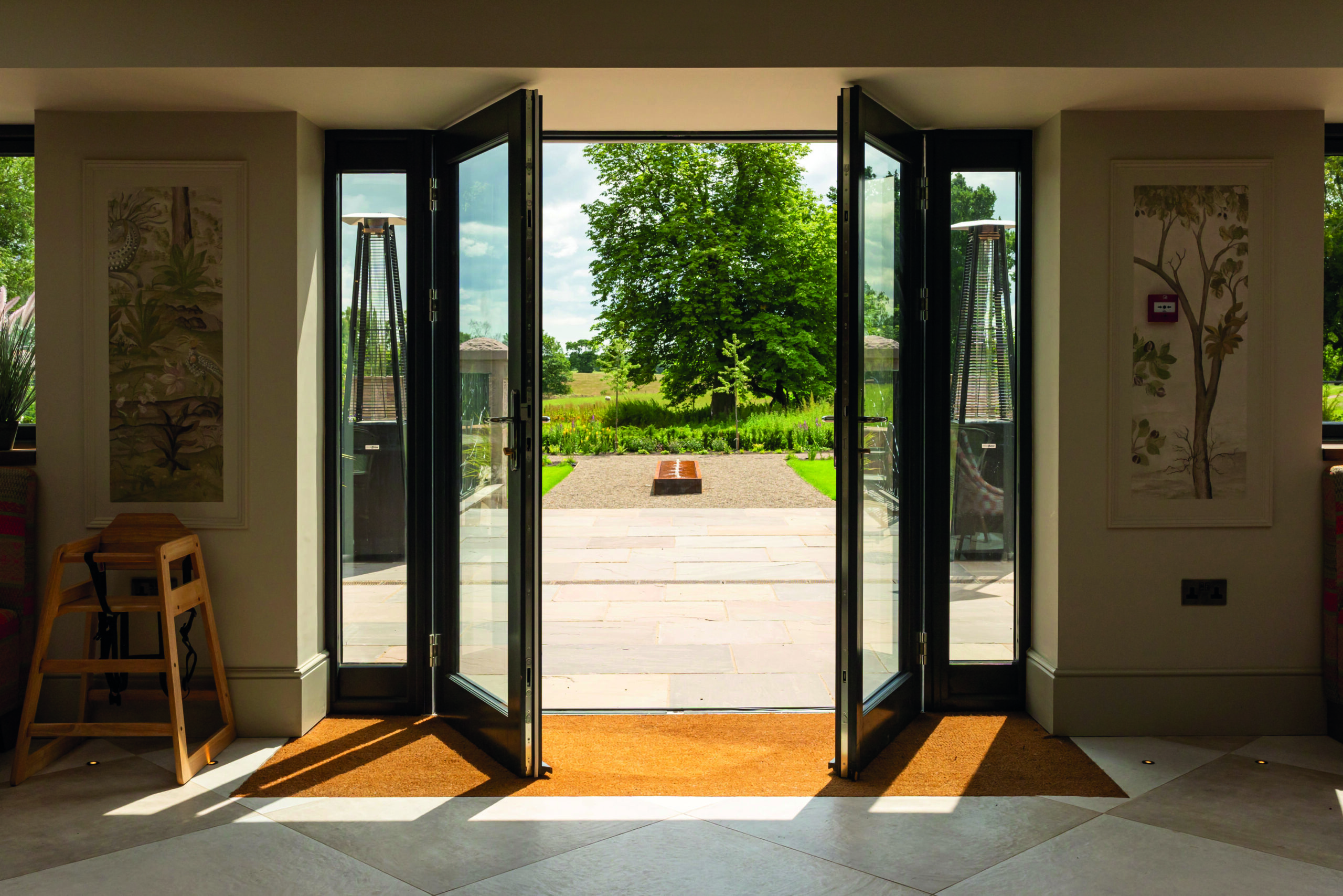 Open doorway reveals a view of a garden and trees.