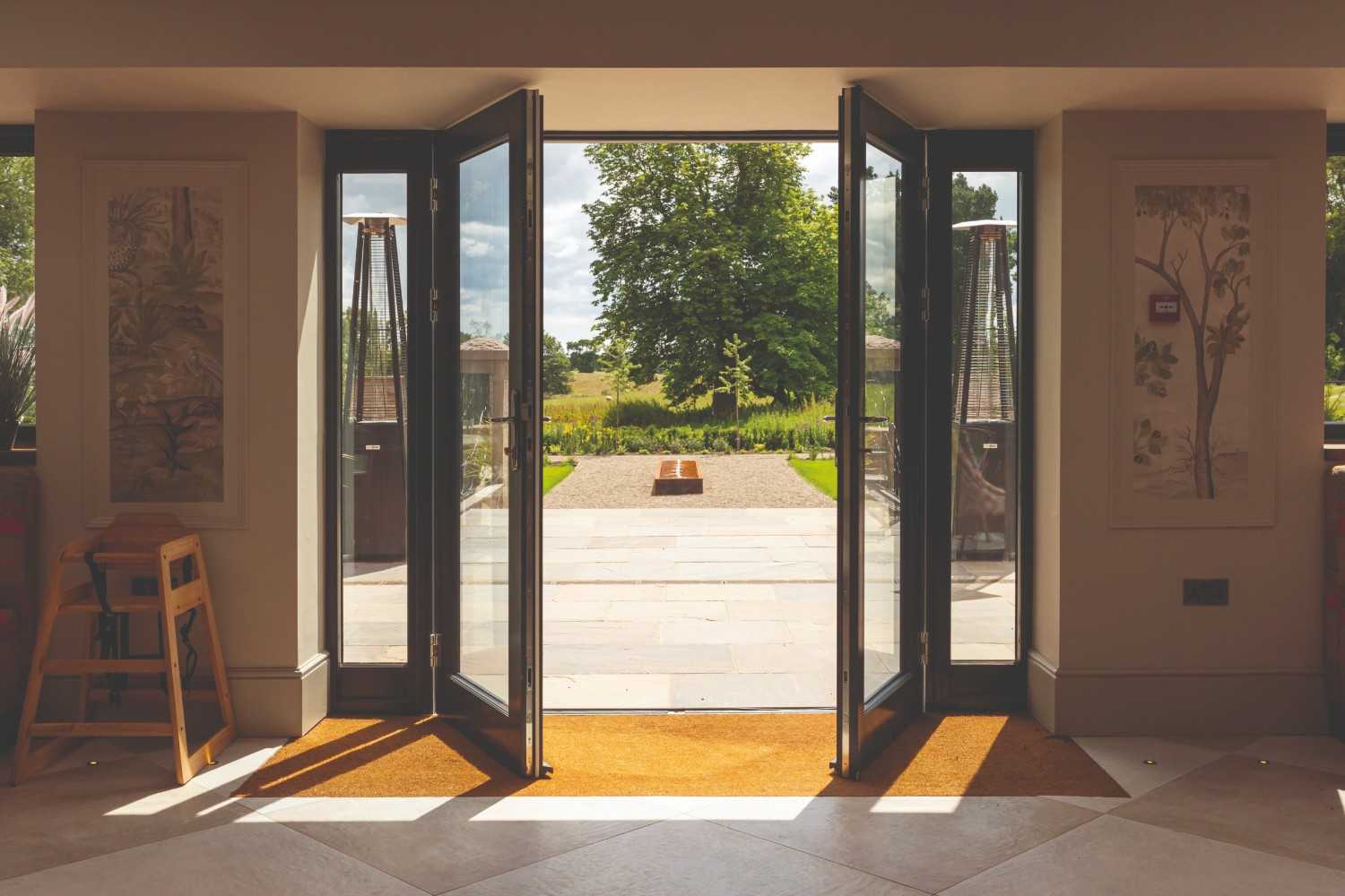Open French doors revealing a sunlit garden view.