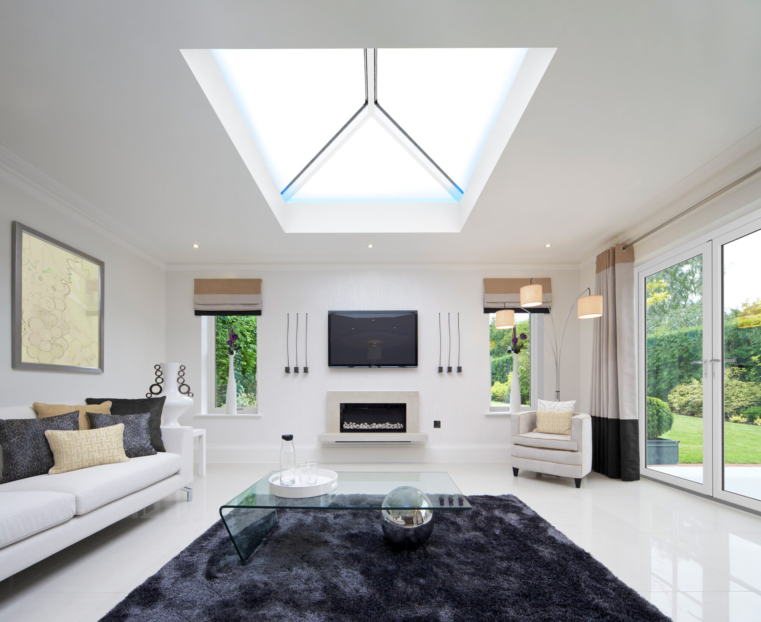 Bright modern living room with skylight, sofa, and glass table.