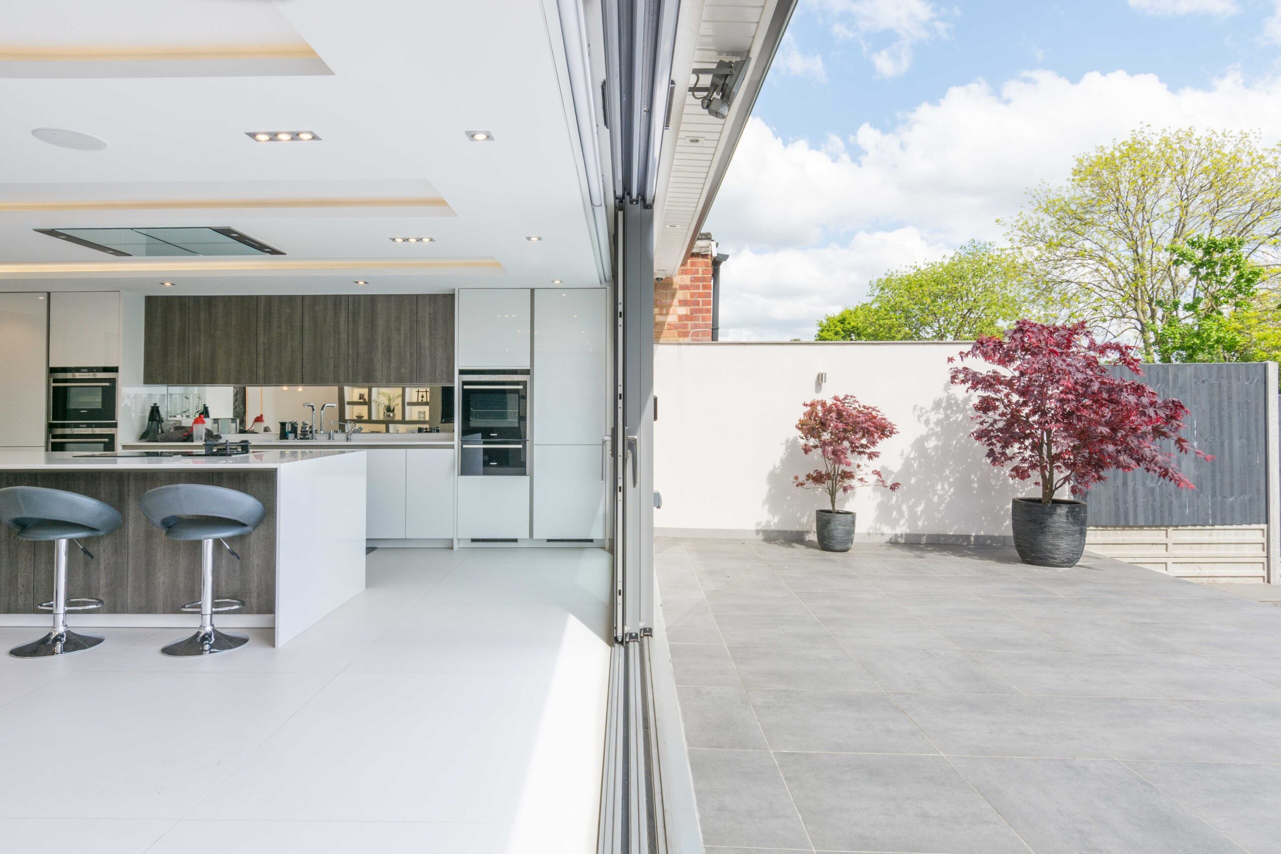 Open kitchen and patio with potted trees and sliding doors.