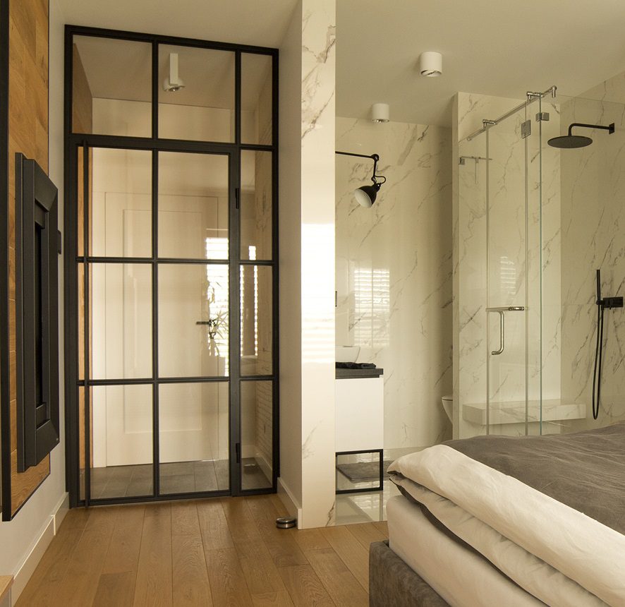 Minimalist bedroom with glass shower enclosure for spa-like modern design.