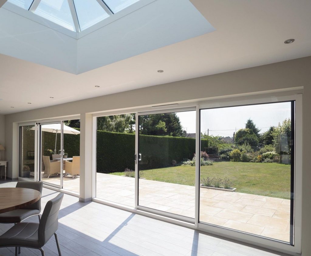 Landscape view of glass-walled house with manicured lawn.