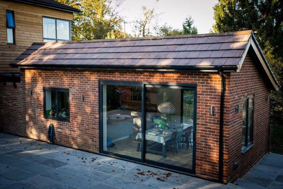 Brick modern extension with glass door showcasing dining inside.