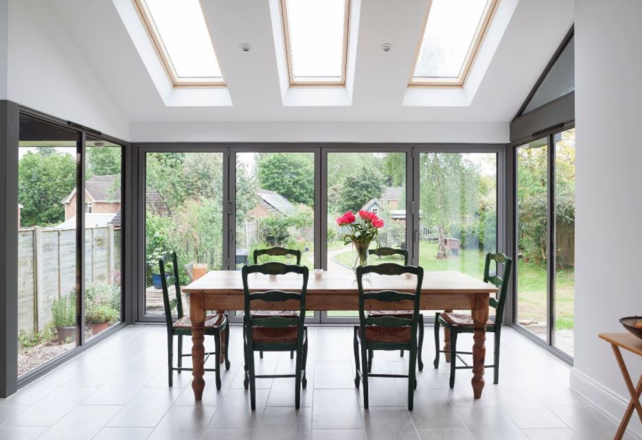 Sunroom with wooden dining table, chairs, skylights, and natural light.