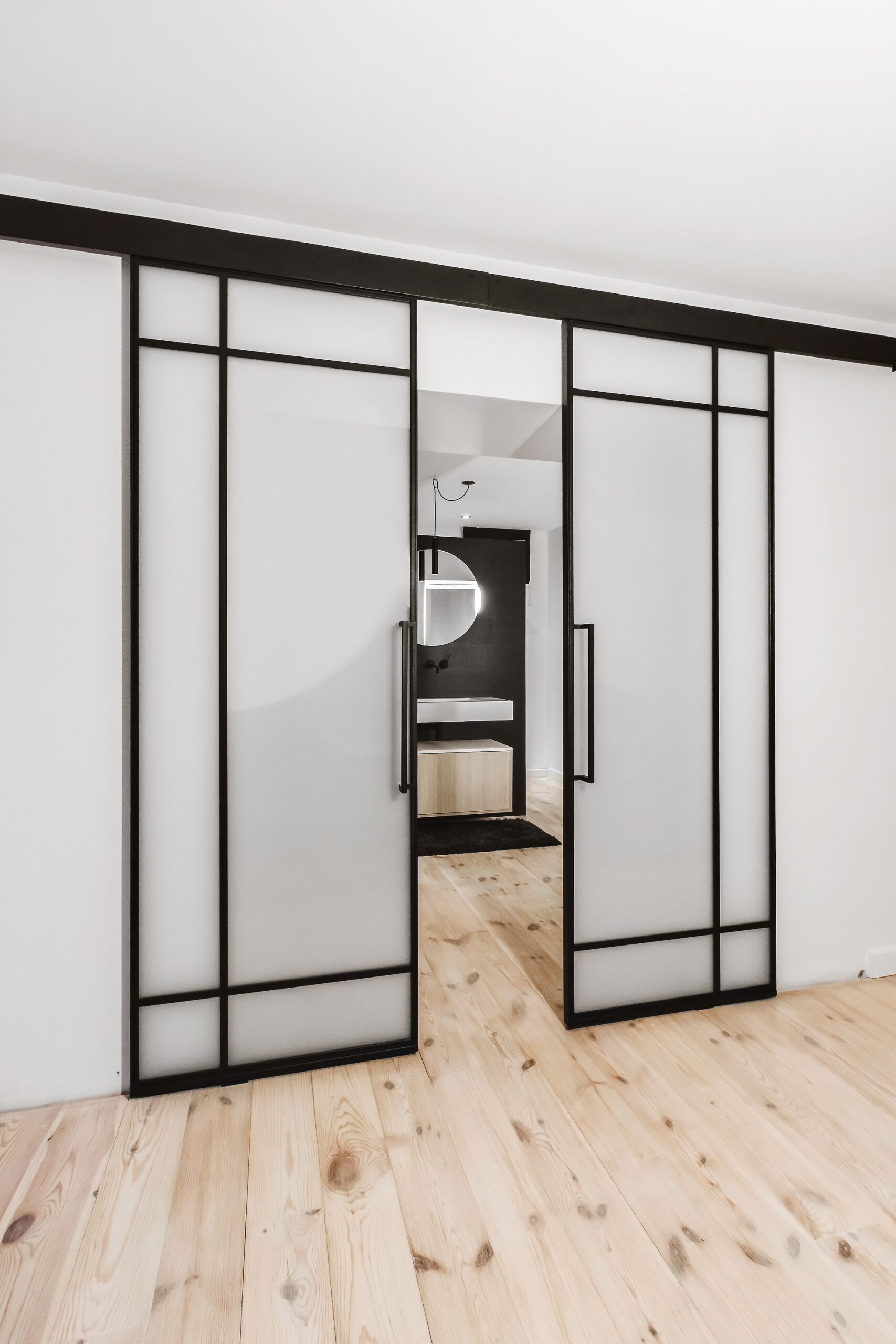 Glass sliding doors opening to garden with modern furniture inside.