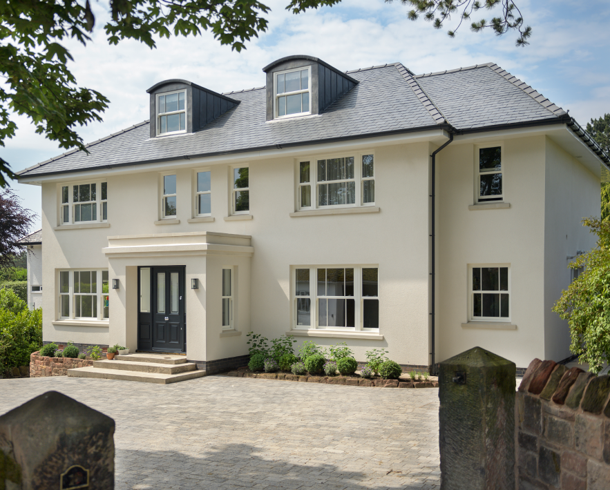 Multi-story white house with black door and greenery.