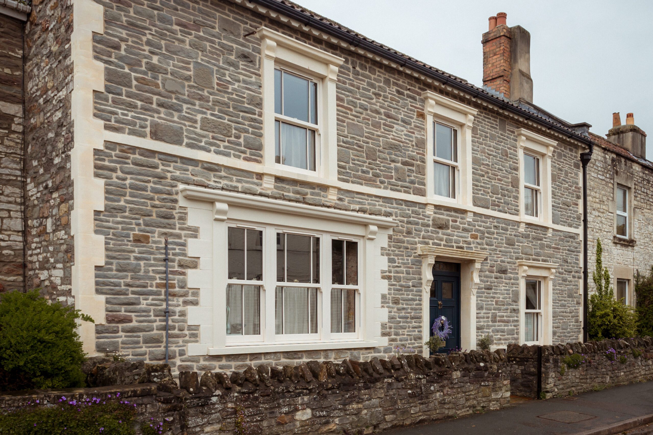 Stone cottage with white-trimmed windows and stone wall accents.