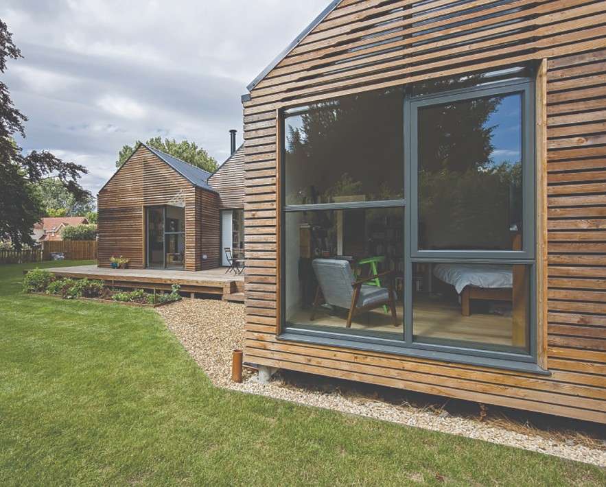 Modern timber-clad home exterior with large grey-framed windows and lawn