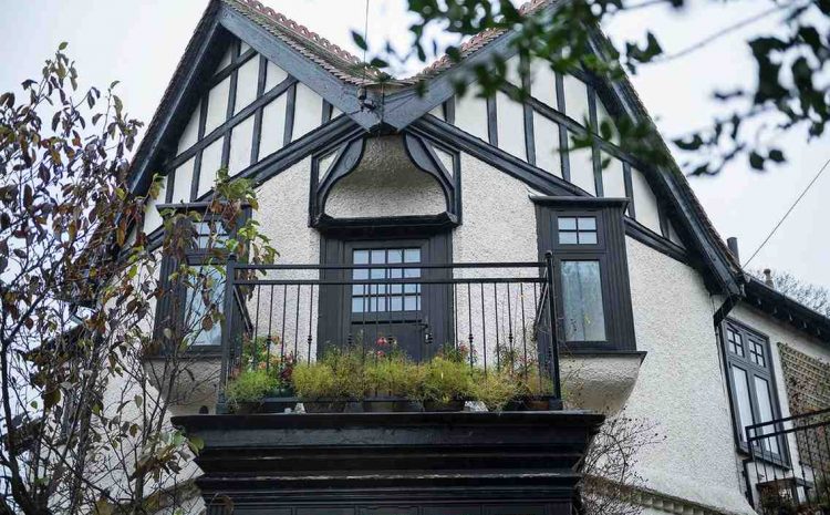 Tudor-style home with second-story balcony and dark wood accents.