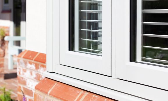 Quaint window view with purple flowers in orange brick planter.