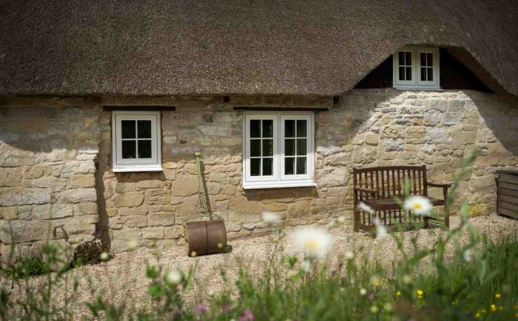 Stone cottage with windows and a wooden bench.