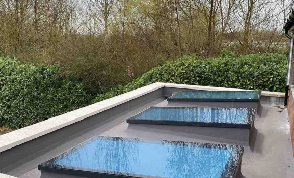 Red brick house with large glass sliding doors reflecting garden.