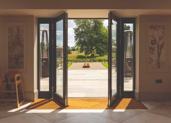 Open French doors revealing a sunlit garden view.