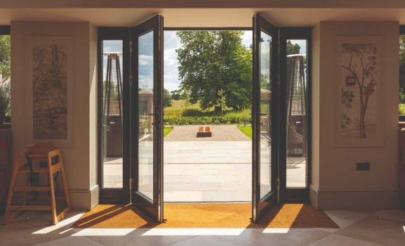 Open French doors revealing a sunlit garden view.