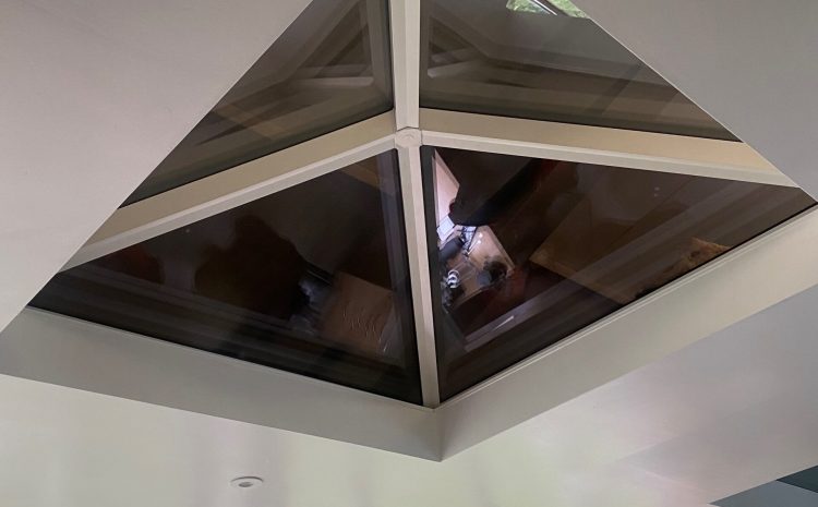 Modern skylight with black and white frame in white-walled room.