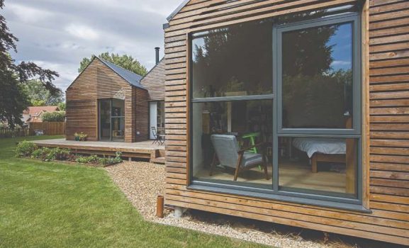 Modern timber-clad home exterior with large grey-framed windows and lawn
