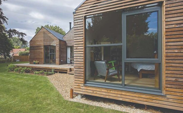 Modern timber-clad home exterior with large grey-framed windows and lawn