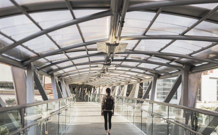 Woman walks along a covered walkway with glass roof.