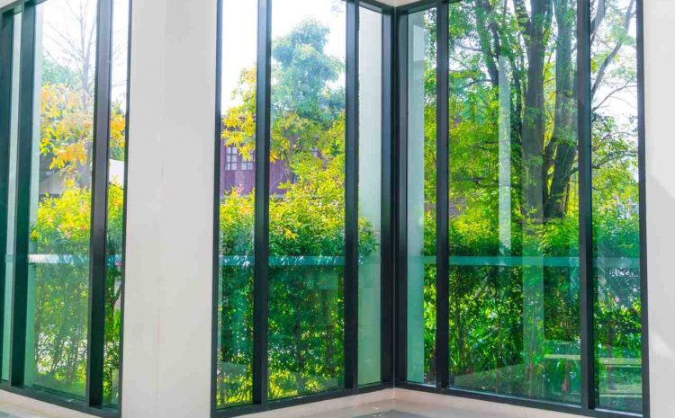 Interior view of large glass windows looking out over a green garden