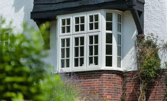 uPVC Casement Windows 3 White uPVC bay casement window on white rendered house with garden flowers